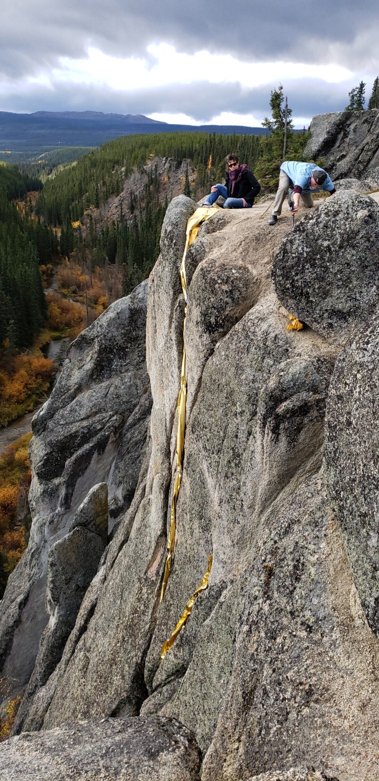 Artists laying golden blankets in the crack of a cliff
