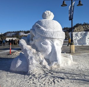 The snow carving titled, "In one ear out the other" was a human head, rising from a hooded parka with a toque sporting a pompom. The snow carving was also a slide for children to walk up the rim of the hood and slide from the upper ear and out the other ear.